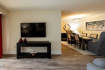 A black coffee table with a TV above it and a red vase on it.